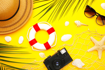 Fototapeta na wymiar Beach accessories with palm leaves on yellow background