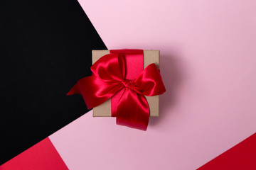 Craft box with a large red bow on a paper background. Flat lay.