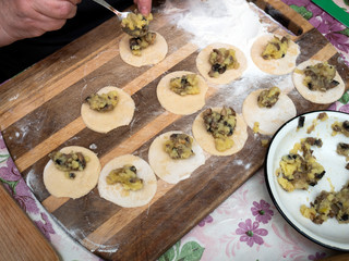 Senior woman is preparing a popular dish of dumplings with potatoes and mushrooms.