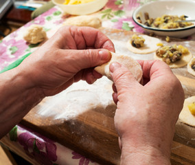 Senior woman is preparing a popular dish of dumplings with potatoes and mushrooms.