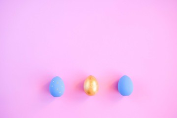 Gold and blue easter eggs on pink background.