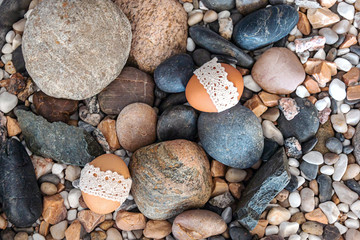 Easter background. Eggs decorated with rustic lace lie on pebble stones of different sizes.