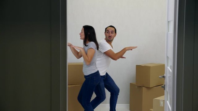 Couple is having fun dacing comically and laughing in their new appartment.