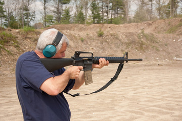 man shooting AR-15 on a range, shell casing in air