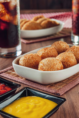 Brazilian appetizer deep fried cheese croquette with mustard and ketchup - Bolinha de queijo