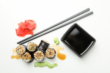 Delicious sushi rolls, soy and chopsticks on white background, top view