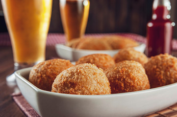 Brazilian appetizer deep fried cheese croquette with two glasses of beer - Bolinha de queiijo