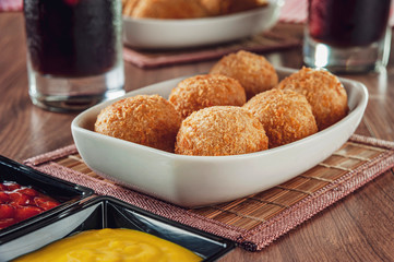Brazilian appetizer deep fried cheese croquettte with mustard and ketchup - Bolinha de queijo