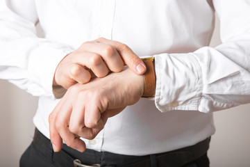 Fototapeta premium Close up of businessman looking at watch on his hand free space. Man in white shirt checking time from luxury wristwatches. Groom wedding preparation.