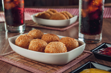 Brazilian appetizer deep fried cheese croquette with two glasses of drink - Bolinha de queijo
