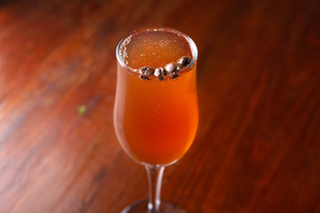 Glass of alcoholic drink with coffee grains on a wooden old table