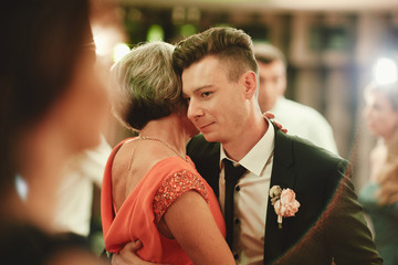 stylish groom is enjoying a dance with his mother on his wedding day. selective focus