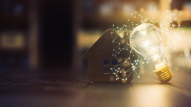 Light bulb with wood house on the table with light line., a symbol for construction, Creative light bulb idea ,Alternative energy, idea, saving electricity innovation and inspiration concepts.