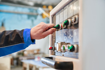 Hand presses a button on the control panel close-up. Concept automated manufacturing factory, modern production technologies