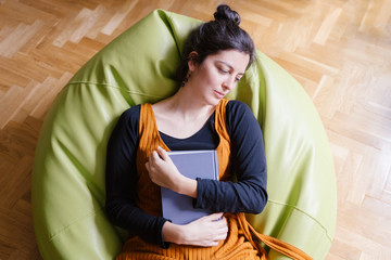 Portrait of worried woman resting at home. Stay home concept. Top view of woman holding a book...