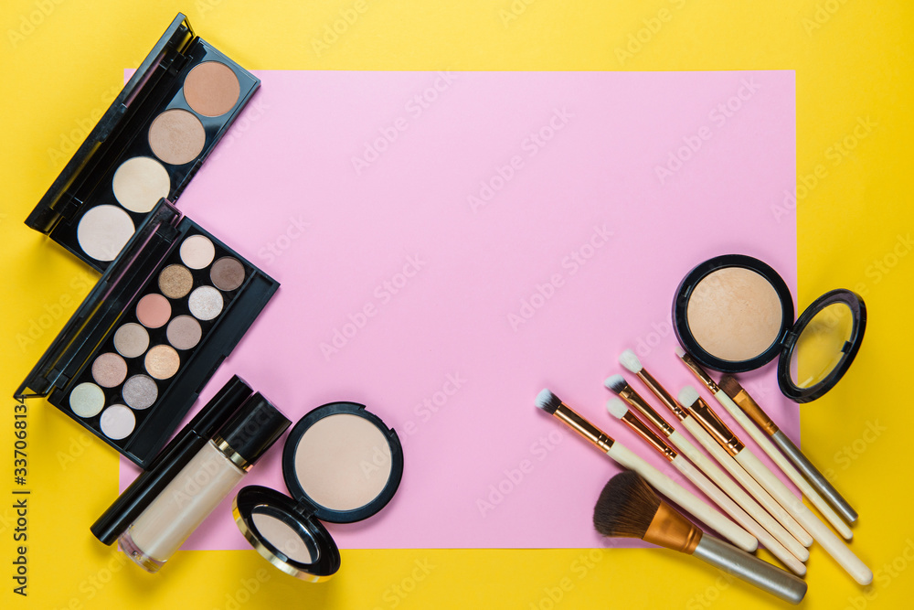 Wall mural makeup brushes, powder, eyeshadow palette, foundation for the face on a light pink and yellow backgr