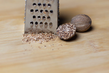 Grated on grater nutmeg close up on wooden background
