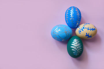 four colored easter eggs on a pink background top view. horizontal image with copy space