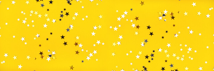 Golden and silver stars on yellow background. Flat lay, top view.