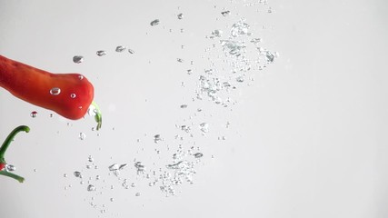 Hot red chilli peppers falling into the water on a white background. Slow motion - Powered by Adobe