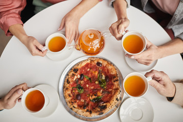 High angle view of family sitting at the table with cups of tea and eating pizza