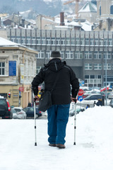 Starszy mężczyzna idący o kulach w zimie