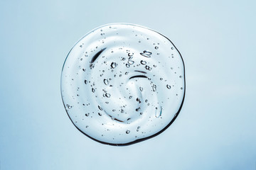 Hyaluronic acid cosmetic gel. Gel texture with bubbles on a blue background. Transparent smear of gel
