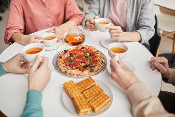 Close-up of family sitting at the table and eating pizza during lunch time at home