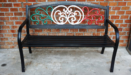 Metal alloy park bench chair painted in Italian flag colors outside an Italian restaurant.