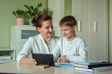 distance learning, online education at home during the covid-19 pandemic. family mom and son joyfully doing homework in the room using tablet