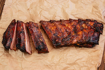 Closeup of pork ribs grilled with BBQ Tasty snack to beer on a paper for filing on dark concrete background. Top view