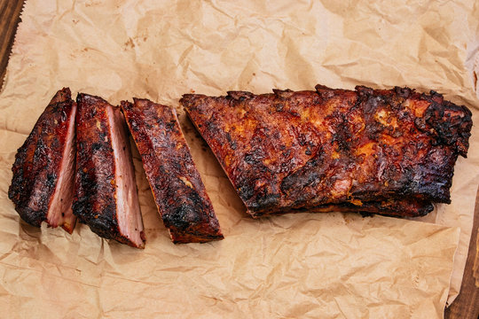 Closeup of pork ribs grilled with BBQ Tasty snack to beer on a paper for filing on dark concrete background. Top view