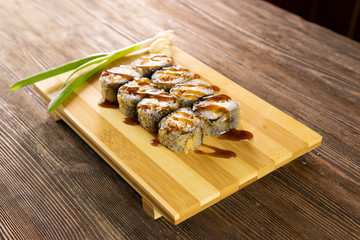 Fried sushi rolls with sauce on wooden board