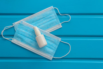 Disposable face mask and bottle with antiseptic on color background. COVID-19 concept