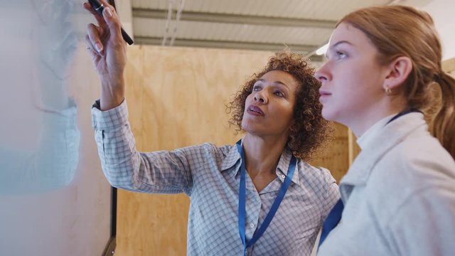 Tutor with trainee electricians studying for apprenticeship looking at wiring diagram on screen - shot in slow motion 