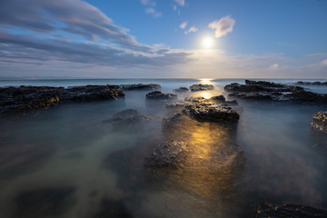 full moon rise over the sea and tidal pools at the beach
