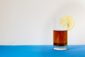 A glass of tea with lemon on the blue table. Support immunity during illness.