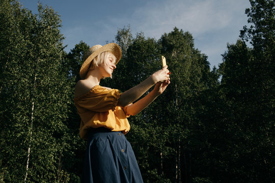 Charming blonde taking photo while resting outdoors