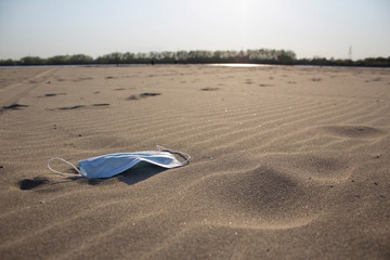 The medical mask is lying on the sand. People are tired of threats and isolation. Coronavirus, the concept COVID-19.