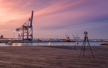 Zeebrugge, Belgium - 31 October 2019: Digital camera on tripod taking a photo of the port of Zeebrugge at sunset © Erik_AJV