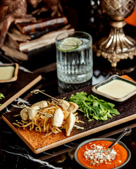 chicken fillet pieces on stick served with shoestrings arugula and sauce