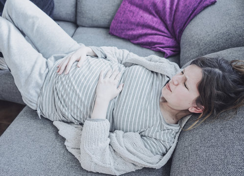 Young pregnant woman suffering pain at home