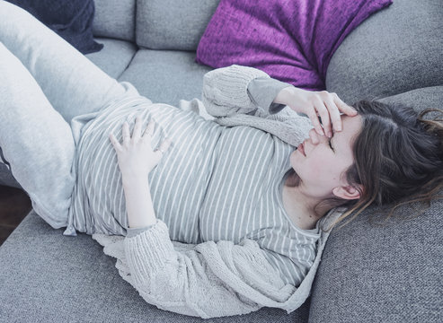 Young pregnant woman suffering pain at home