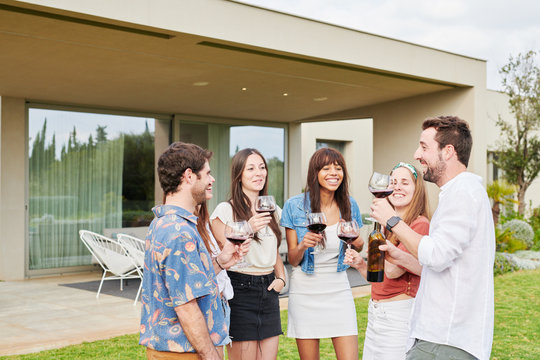 Happy friends gathering with wine in garden.