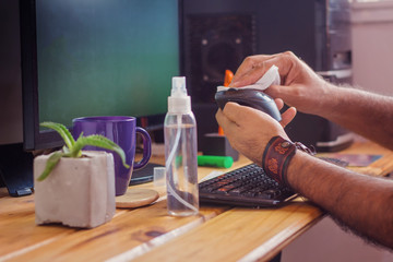 man disinfecting a mouse with alcohol in a homeoffice