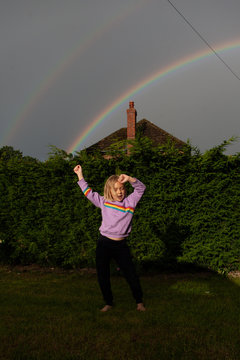 Rainbow magic. A girl dances in the rain.
