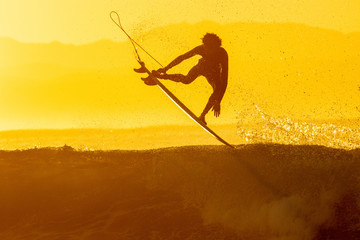 Fototapeta na wymiar silhouette of a surfer doing an air at sunrise