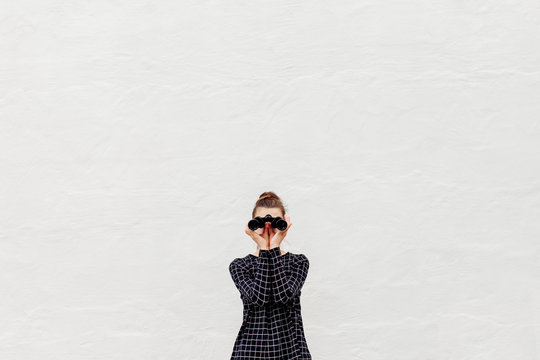 Preteen girl facing the camera while looking into a pair of binoculars