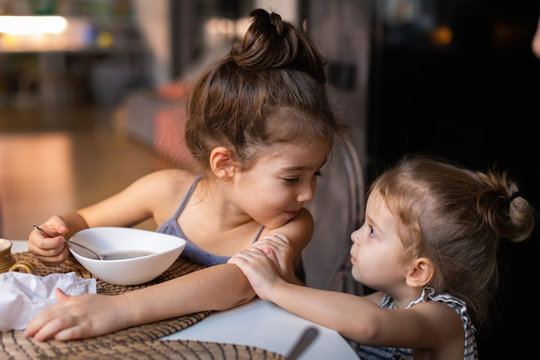 Little girl bothering her sister having soup at table