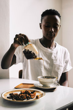 Young Black Woman Pouring Tea into Cup